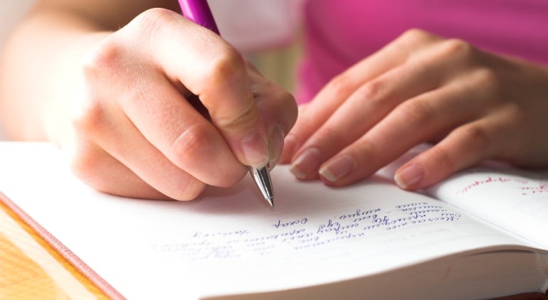 Imagen de una chica escribiendo en un cuaderno.