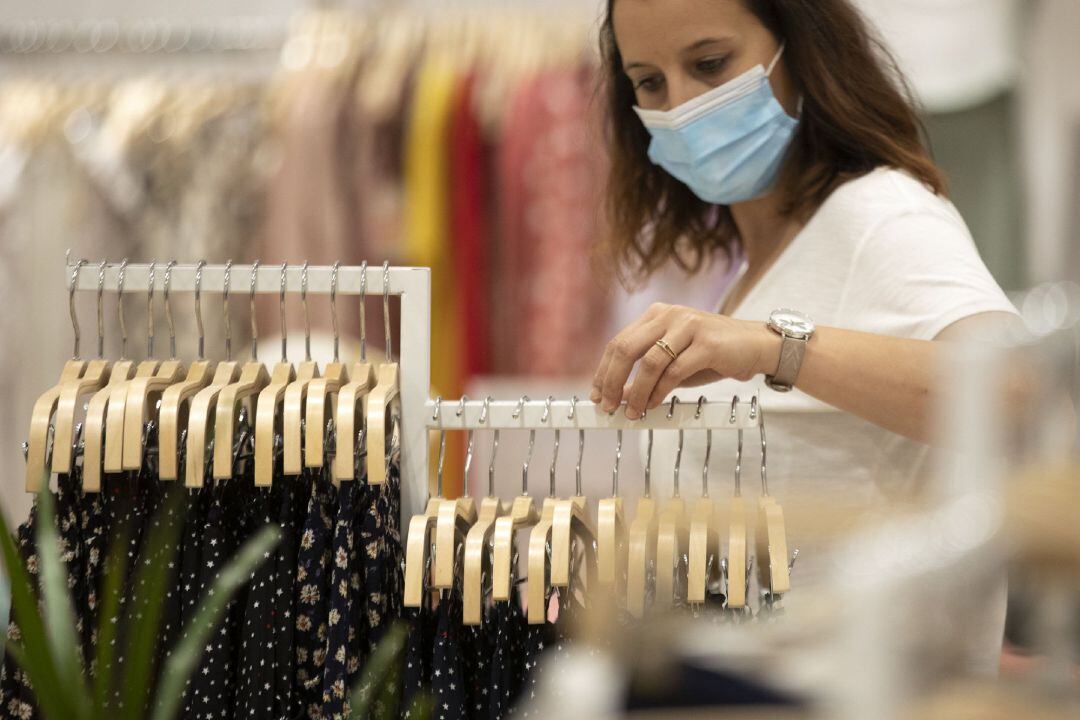 Archivo - Mujer con mascarilla en una tienda de ropa.