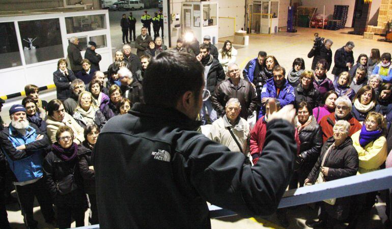 El vicepresident de la Plataforma d'Afectats de la Cooperativa de Cambrils parla, d'esquenes, davant una multitud d'afectats a la nau de l'entitat.