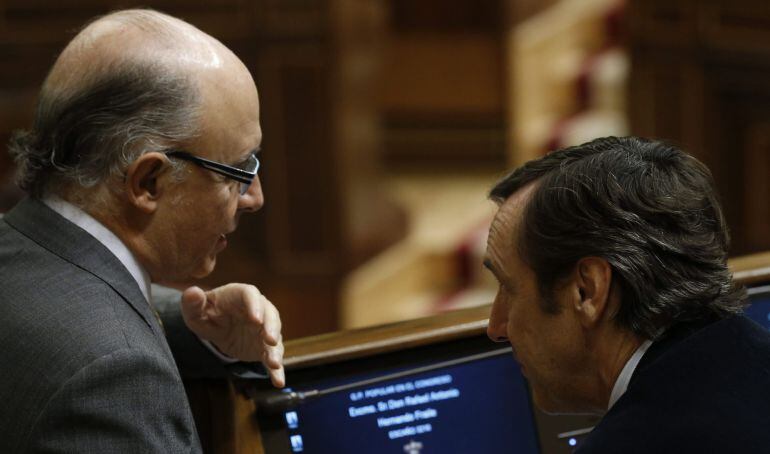 El ministro de Hacienda, Cristóbal Montoro,iz, conversa con el nuevo portavoz parlamentario del PP, Rafael Hernando,d., durante la sesión de control al Gobierno celebrada hoy en el pleno del Congreso.