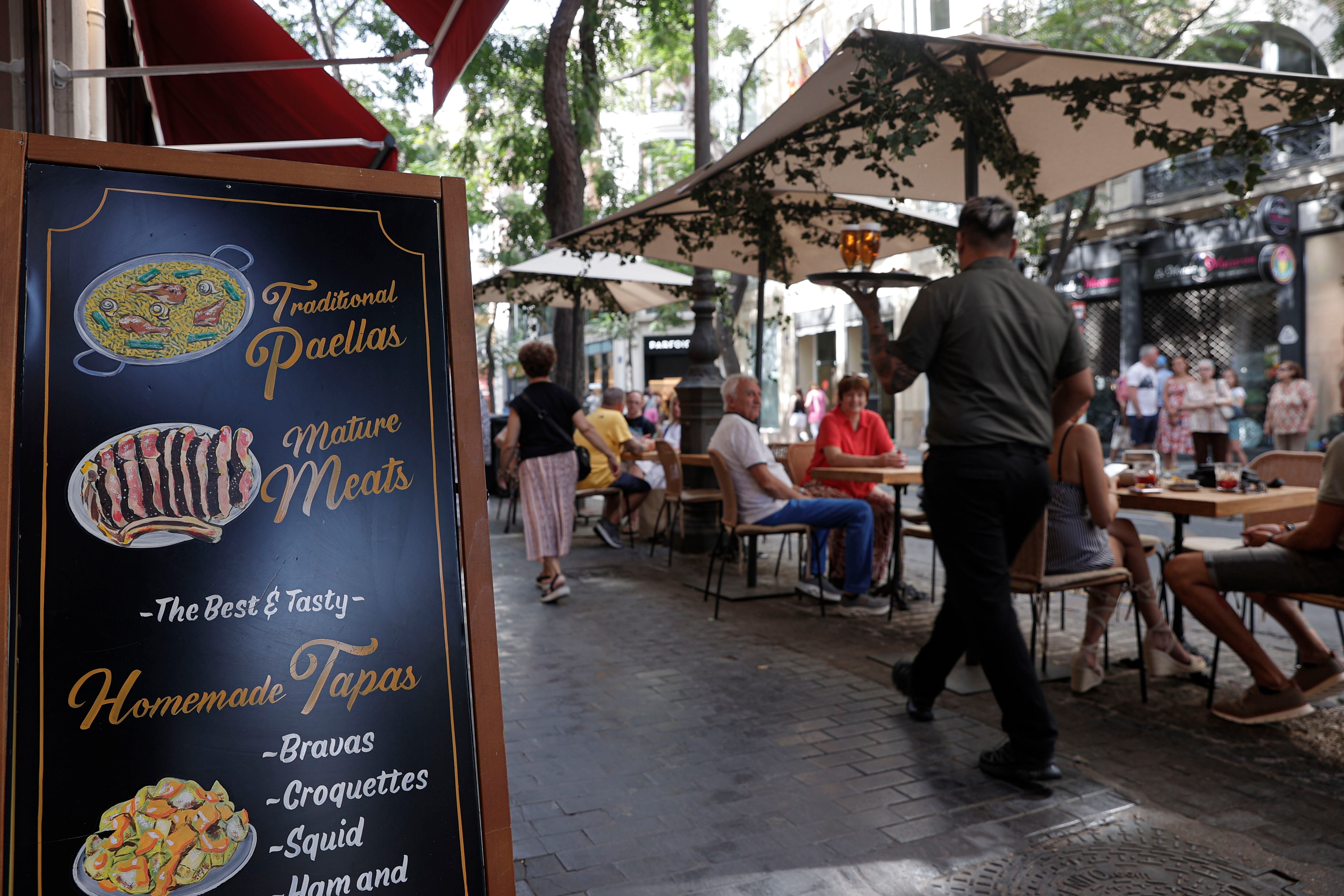 Un camarero lleva unas bebidas a unos clientes en una terraza del centro histórico de València.