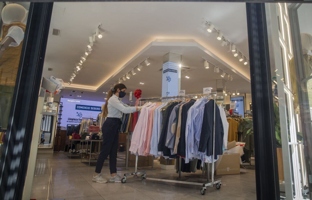 Una empleada de una tienda de ropa con mascarilla y guantes, en Sevilla