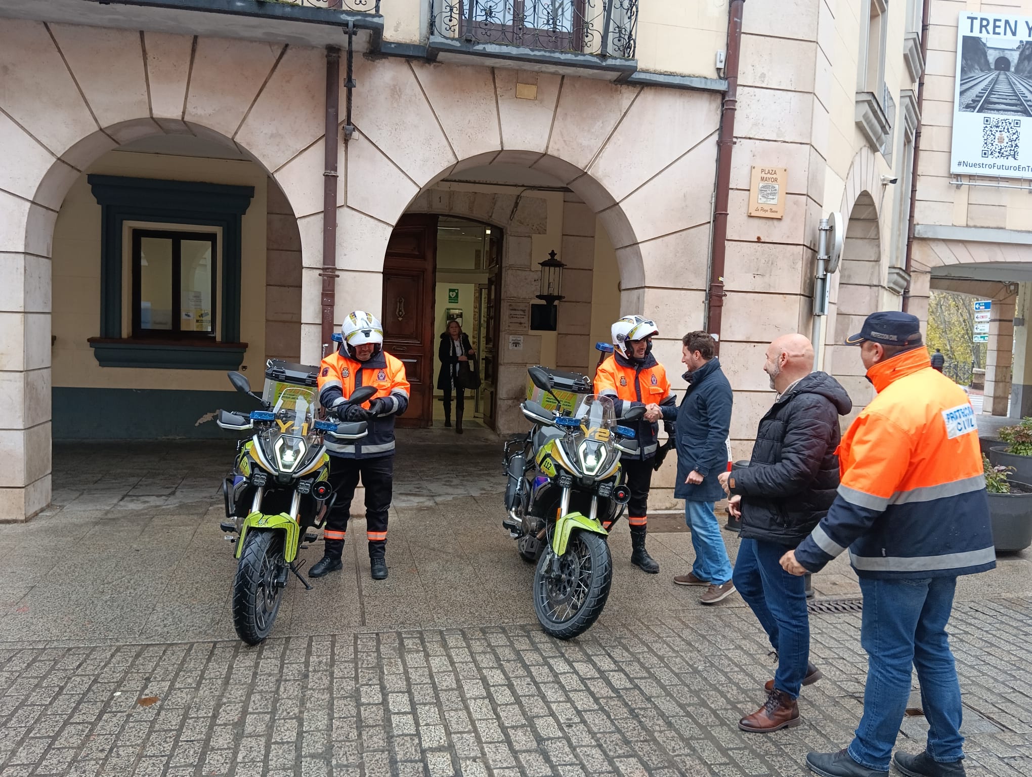 El alcalde (al fondo), el concejal de Seguridad Ciudadana, Juan Manuel Martín, y el jefe de la agrupación de voluntarios saludan a los miembros de la agrupación que han conducido las motos para su presentación