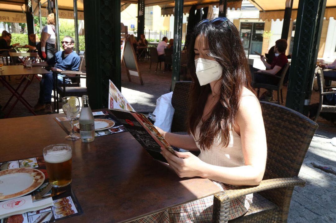  Una mujer sentada en una terraza ojea la carta de menús 