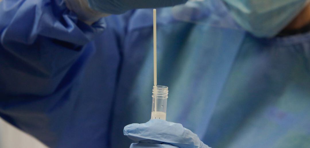 Una trabajadora sanitaria sostiene una probeta con una prueba PCR