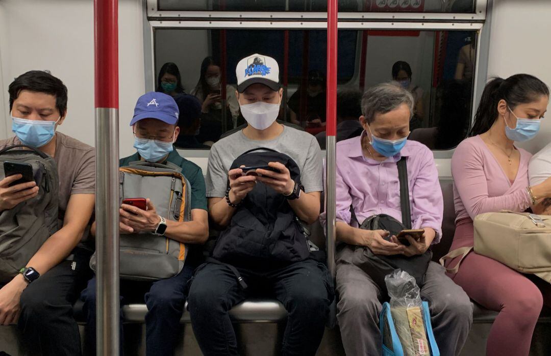 Cinco pasajeros con mascarilla sentados en un vagón de metro sin distancia de seguridad en Hong Kong (China), donde los rebrotes siguen creciendo. 