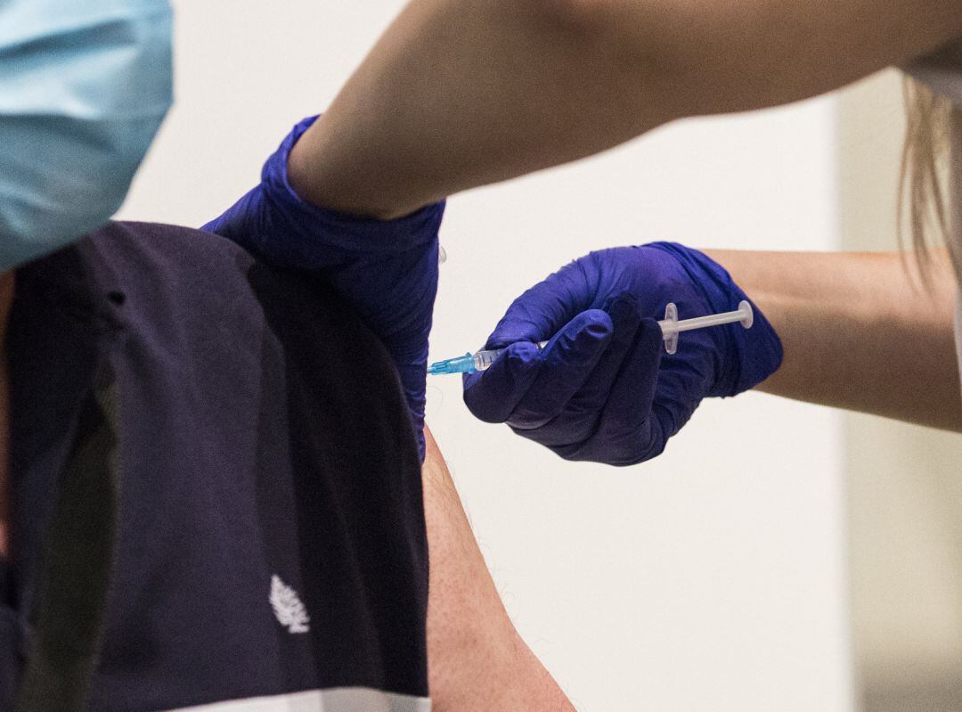 Una sanitaria administra la primera dosis de la vacuna de Pfizer a un hombre.