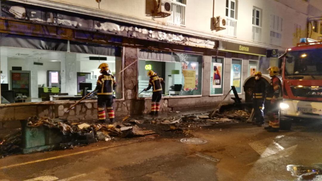 Bomberos de Lanzarote retirando los restos del incendio de la sucursal bancaria afectada.