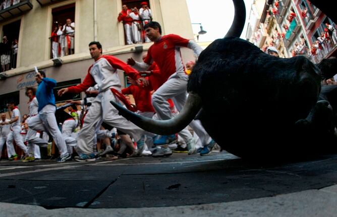 Uno de los toros cae en la esquina de la calle Estafeta durante el segundo encierro