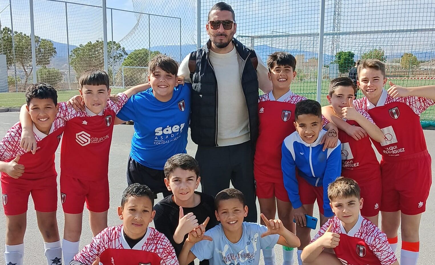 Chico Flores rodeado de jóvenes futbolistas.