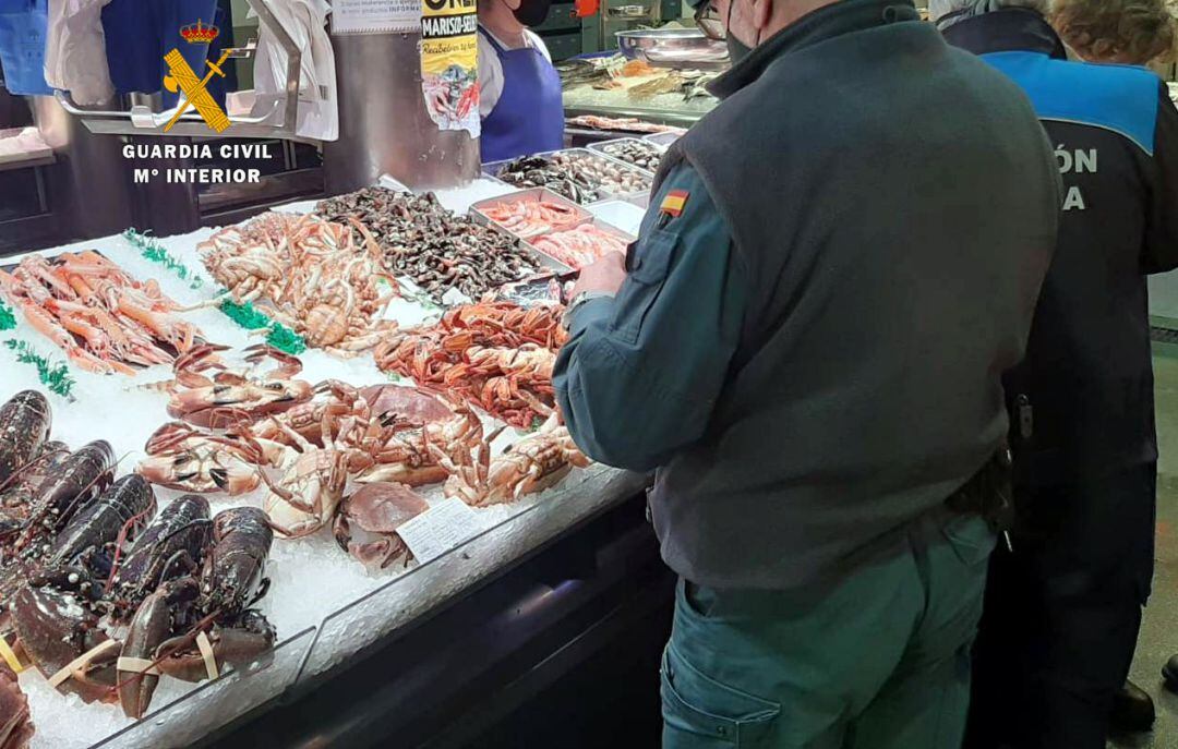 Un guardia civil inspeccionando un puesto de venta de marisco.