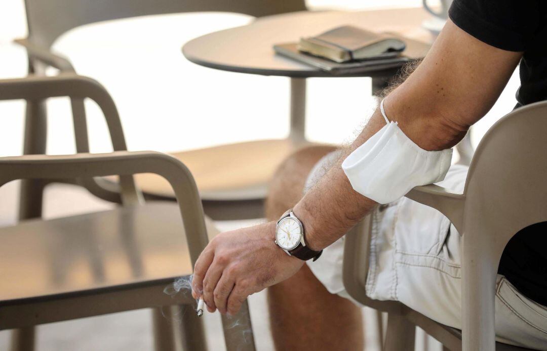 Un hombre fuma un cigarro este viernes en València, en el día en el que se ha anunciado la prohibición de fumar en la calle si no se cumple la distancia de dos metros.