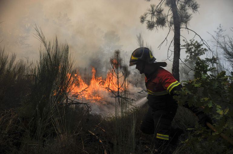 Un efectivo de protección civil realiza labores de extinción en el incendio forestal en la parroquia de Cudeiro, a las afueras de Ourense