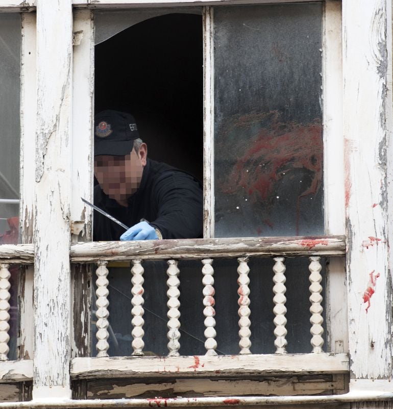 Un ertzaina toma pruebas en la ventana del domicilio donde ocurrió la tragedia