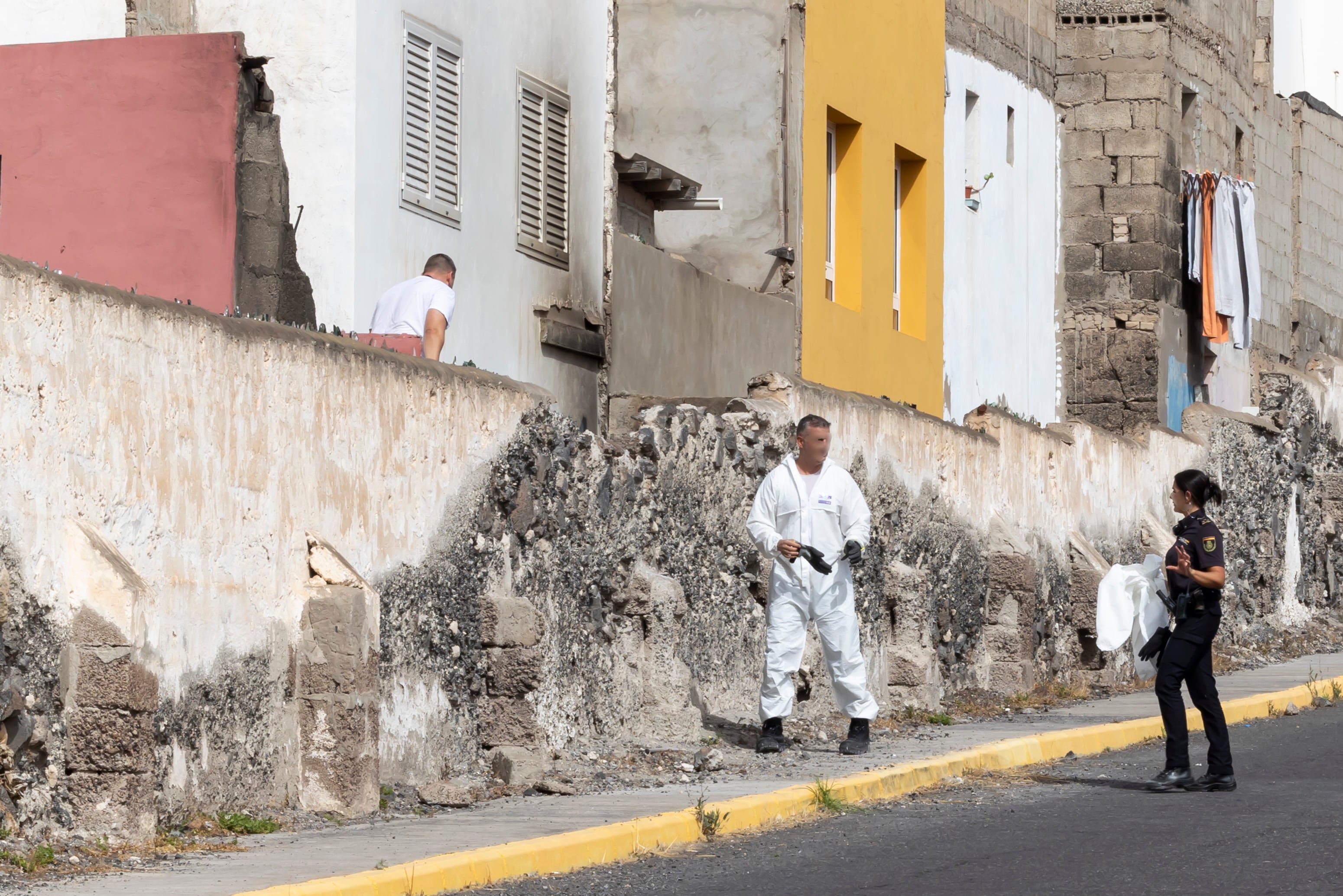La Policía Nacional ha detenido esta madrugada a un joven acusado de provocar quemaduras muy graves con material combustible a una menor de 17 años en una vivienda del barrio de La Isleta de Las Palmas de Gran Canaria. En la imagen, agentes policiales registran el inmueble donde sucedieron los hechos.