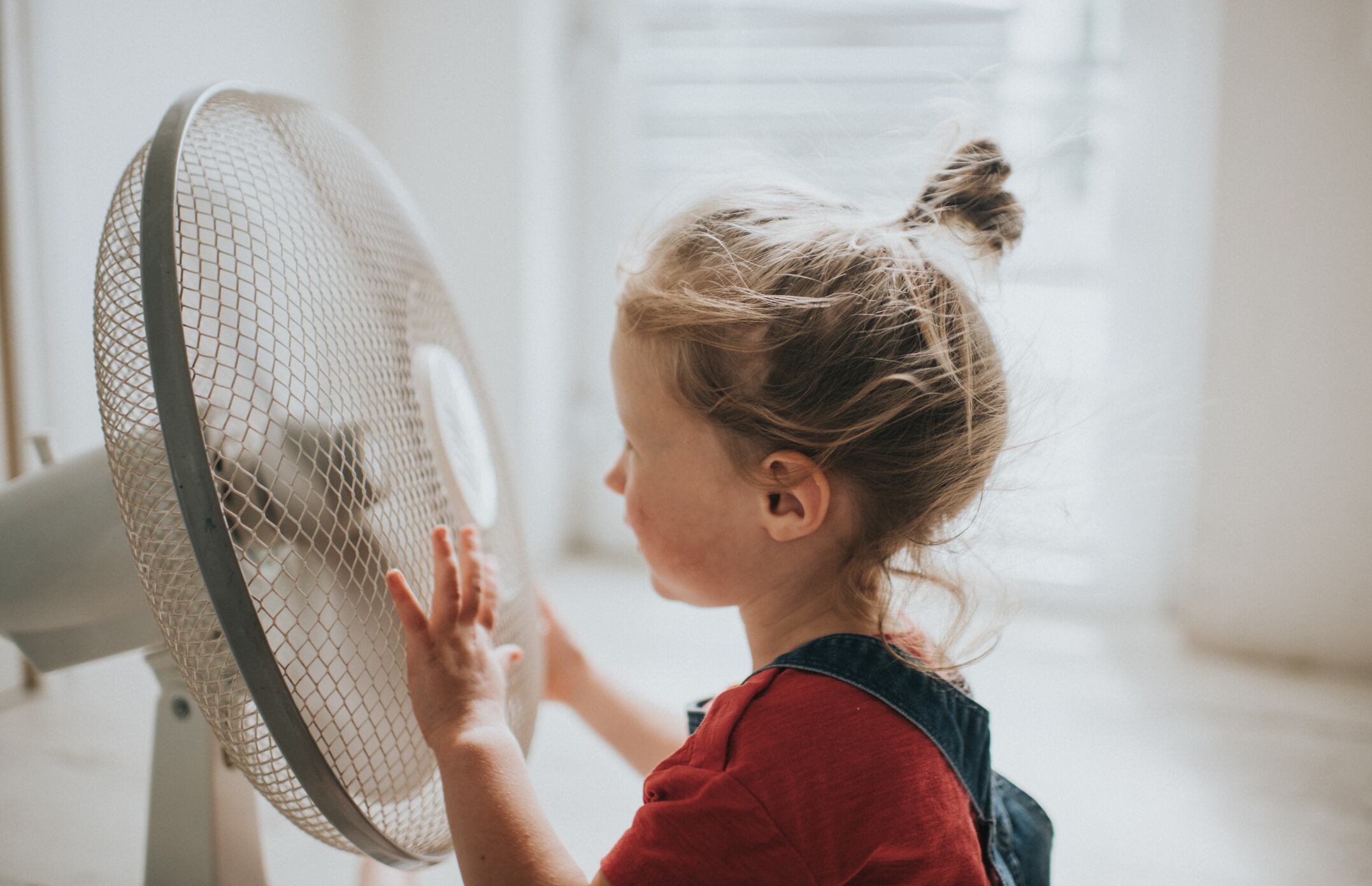 Una niña junto a un ventilador