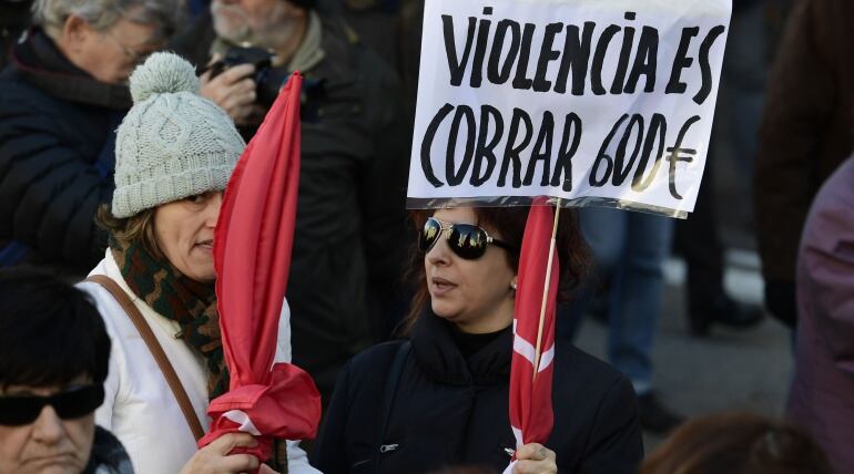 Una mujer sostiene una pancarta reivindicativa durante una manifestación de protesta por los bajos salarios.