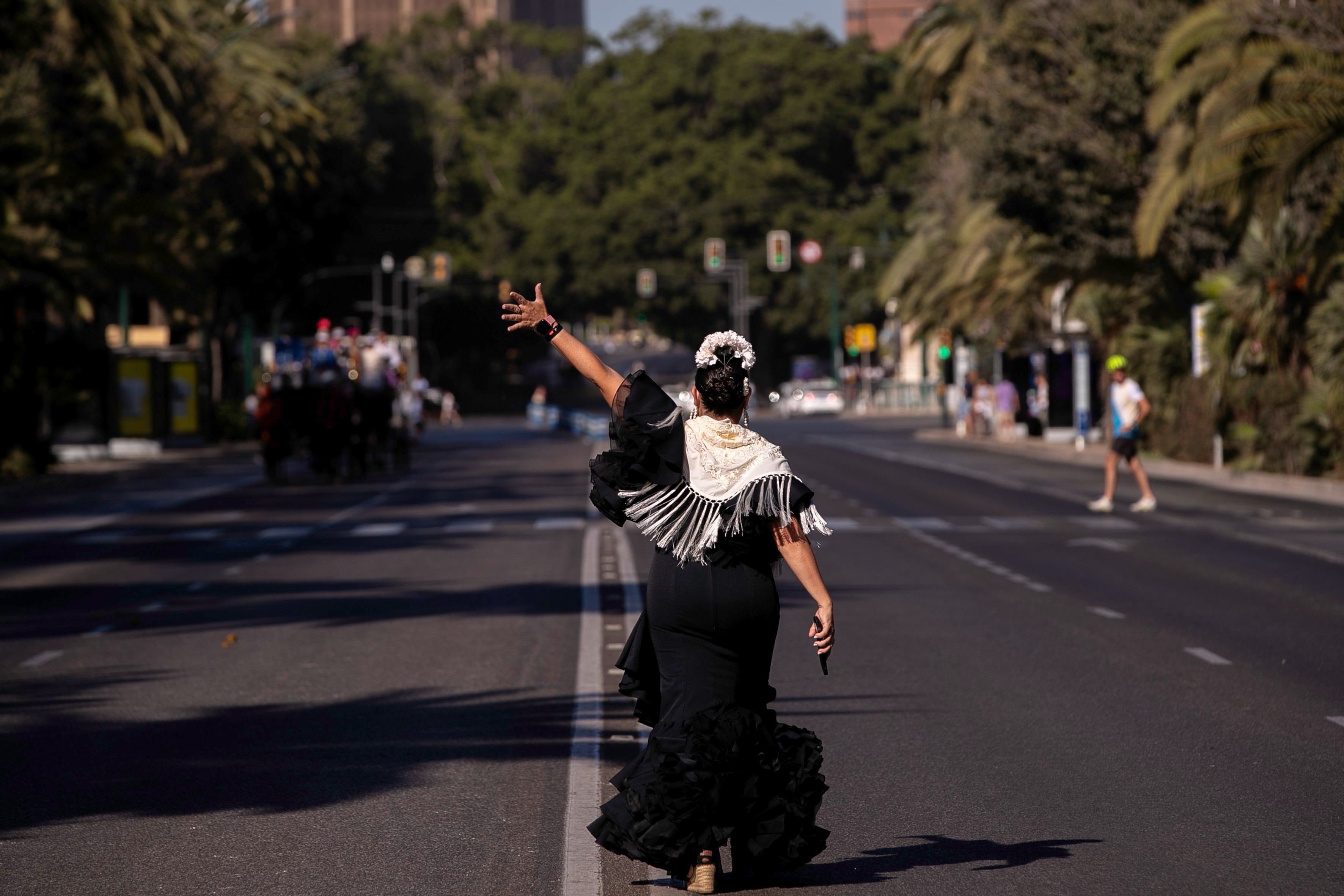 MÁLAGA, 17/08/2024.- Una mujer vestida de flamenca saluda al inicio de la romería al Santuario de la Victoria, hoy en el primer día de la Feria de Málaga. EFE/Jorge Zapata
