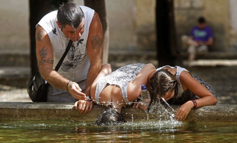 Turistas se refrescan en la fuente del Patio de los Naranjos