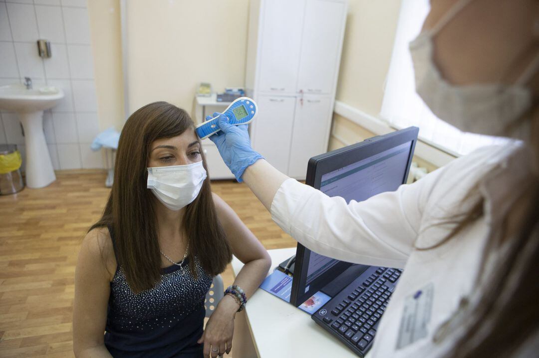 Una trabajadora sanitaria mide la temperatura de una voluntaria antes de aplicarle la vacuna rusa Sputnik V en la tercera fase de ensayos.