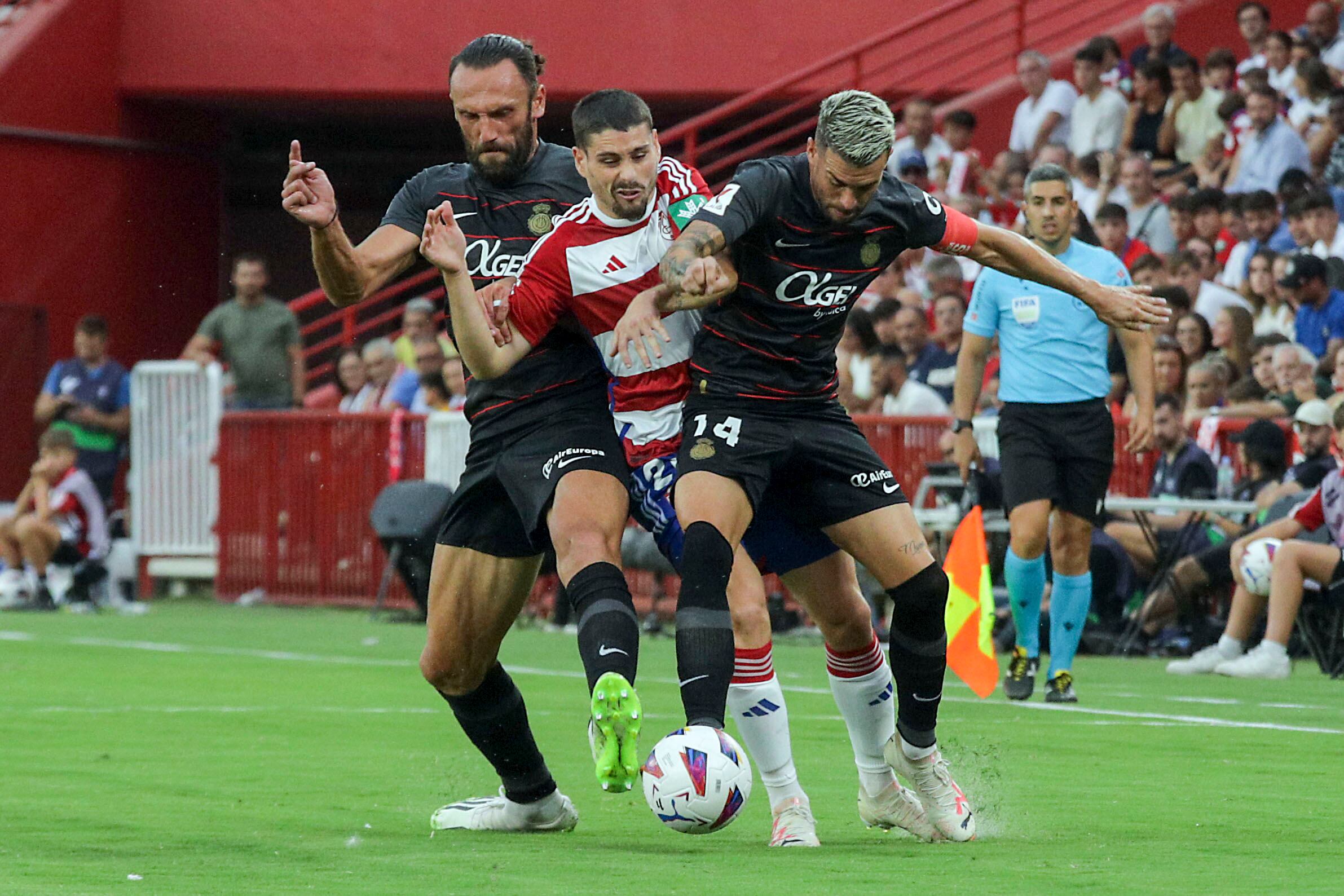 GRANADA 26/08/2023.- El centrocampista del Granada Sergio Ruiz (c) pelea un balón con dos jugadores del Almería, durante el partido correspondiente a la tercera jornada de LaLiga que les enfrenta al RCD Mallorca este sábado en el Nuevo Estadio de Los Carmenes. EFE/Pepe Torres
