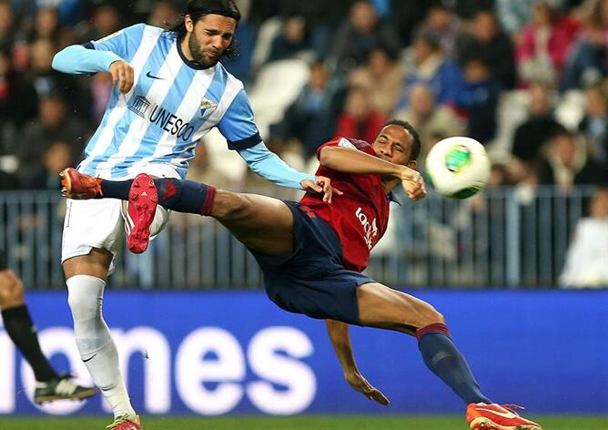 El delantero de Osasuna, Manuel Onwu, cae ante el jugador del Málaga, Sergio Sánchez, durante el partido de ida de los dieciseisavos de final de la Copa del Rey que se disputa esta noche en el estadio de La Rosaleda