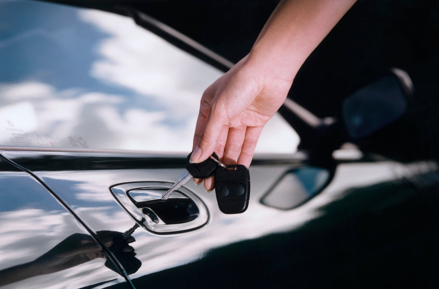 Una mujer abriendo la puerta de un coche.