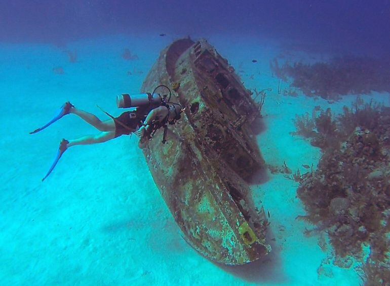 Un submarinista inspecciona una nave hundida.