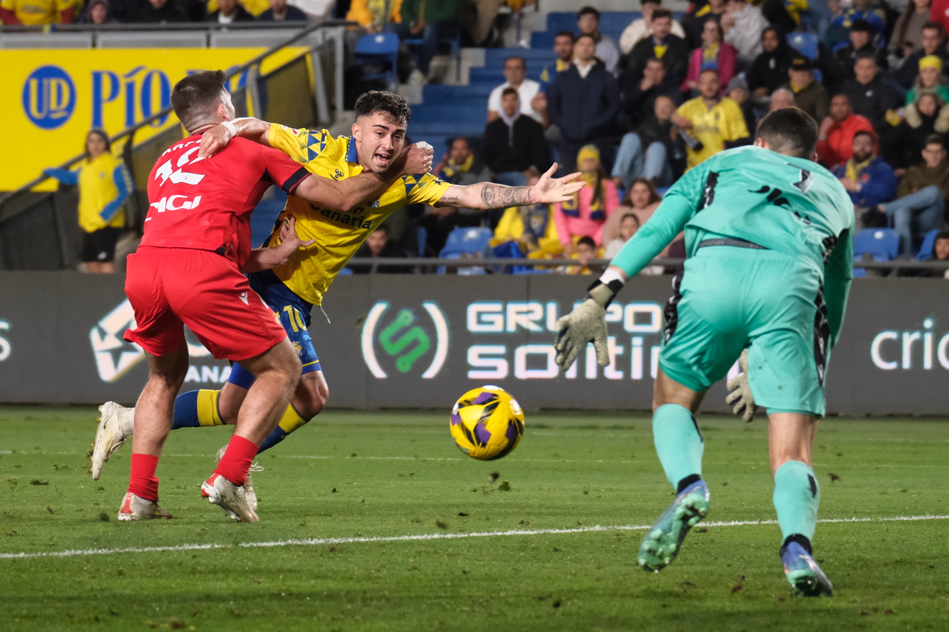 LAS PALMAS DE GRAN CANARIA, 24/01/2025.- El centrocampista de Las Palmas Alberto Moleiro (c) intenta escaparse de Jesús Areso (i), de Osasuna, durante el partido de LaLiga entre la UD Las Palmas y el Osasuna, este viernes en el estadio de Gran Canaria. EFE/ Angel Medina G.
