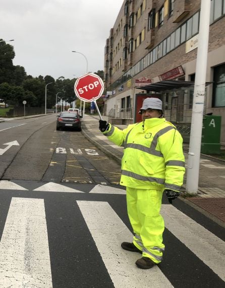 Antonio, voluntario de los caminos escolares, regula el tráfico en un cruce del barrio de Monte Porreiro.