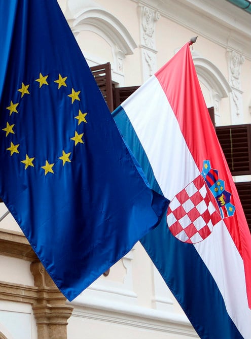 Banderas de Croacia (dcha) y la Unión Europea (izda) ondean en un edificio gubernamental en Zagreb