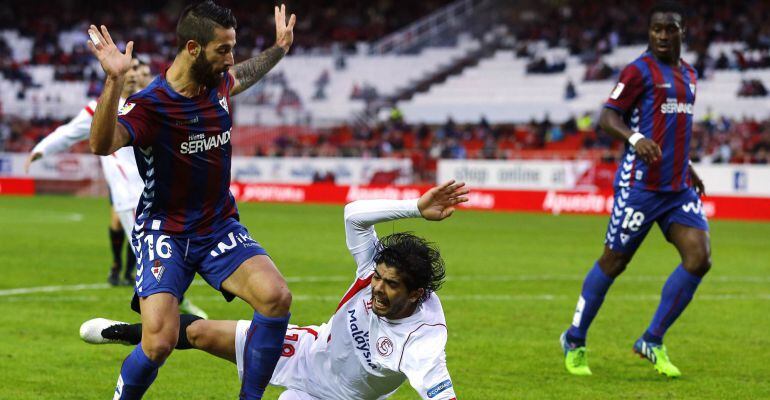 Sevilla's Ever Banega (bottom) is tackled by Eibar's Manuel Castellano "Lillo" during their Spanish First Division soccer match at Ramon Sanchez Pizjuan stadium in Seville, December 14, 2014. REUTERS/Marcelo del Pozo (SPAIN - Tags: SPORT SOCCER)