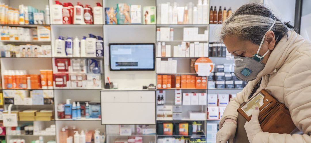 Una mujer acude a una farmacia para recoger una mascarilla