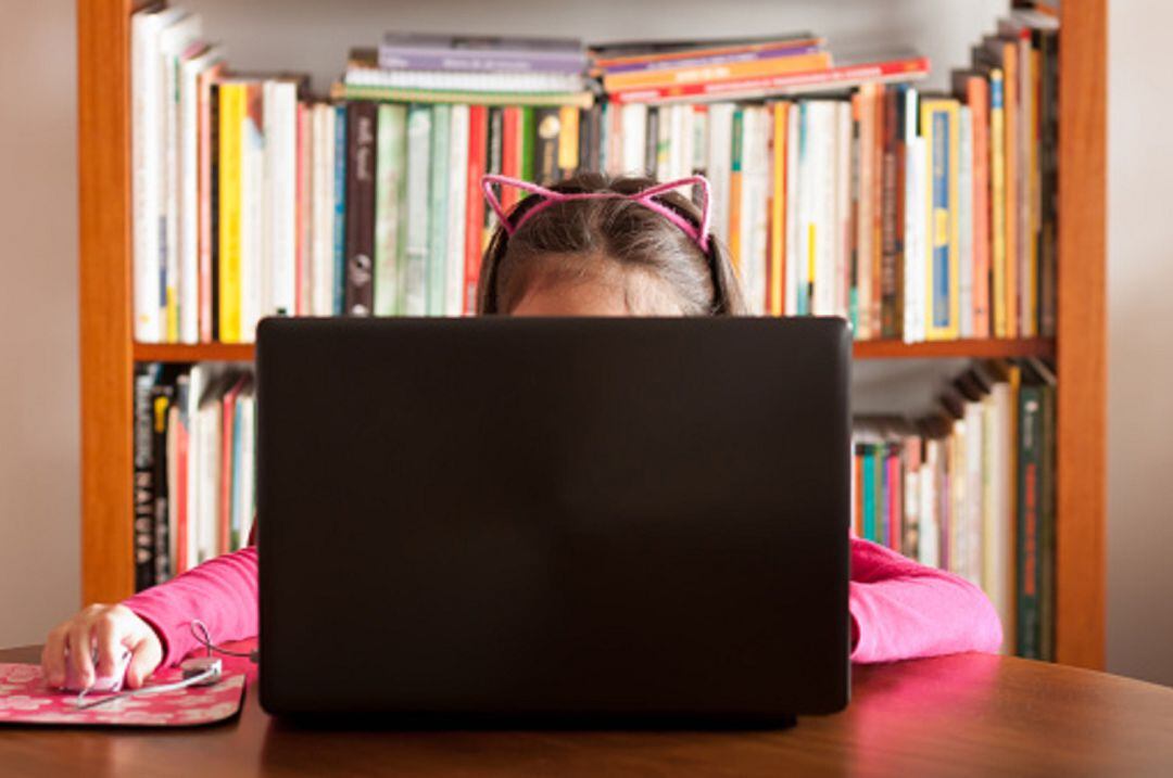 Niña estudiando en casa con un portátil 