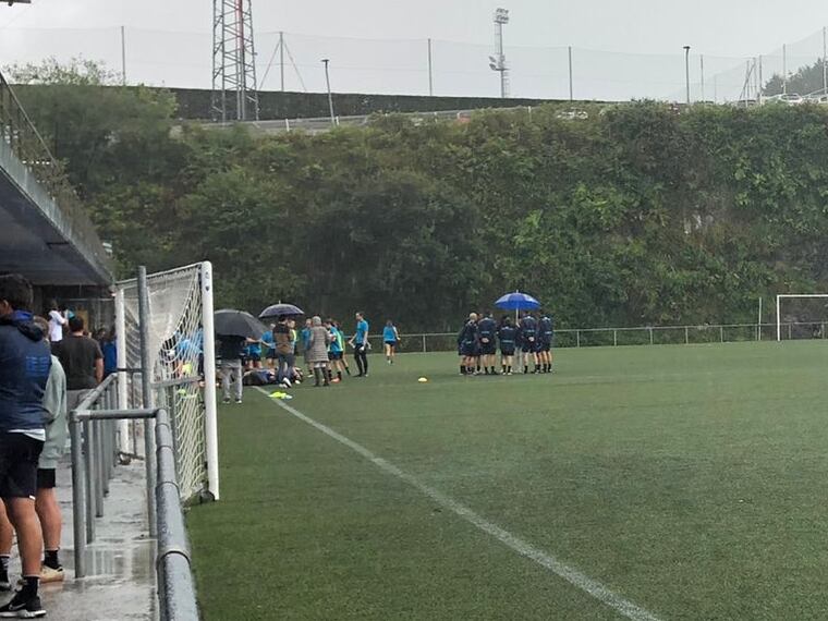 Los técnicos y las jugadoras se reúne bajo la lluvia tras la primera sesión