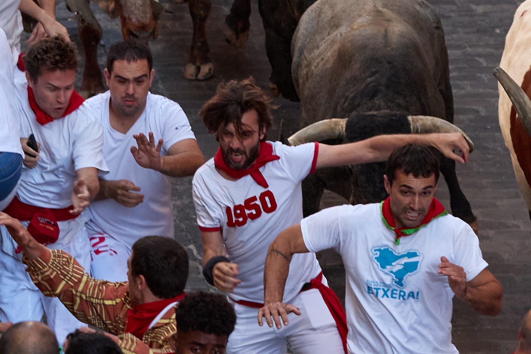 Los mozos corren ante los toros de la ganadería José Escolar Gil, durante el tercer encierro de San Fermín, con los toros de la ganadería de José Escolar, en el tramo que va desde el final de la cuesta de Santo Domingo a la curva de Mercaderes