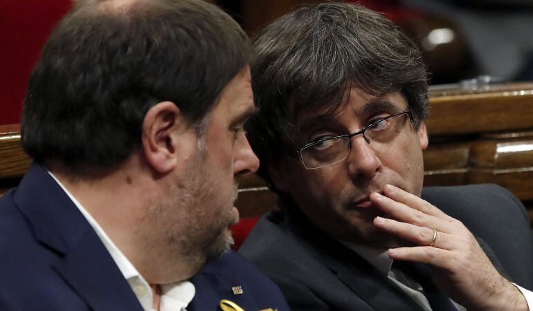 El presidente de la Generalitat, Carles Puigdemont, conversa con el vicepresidente, Oriol Junqueras (i).