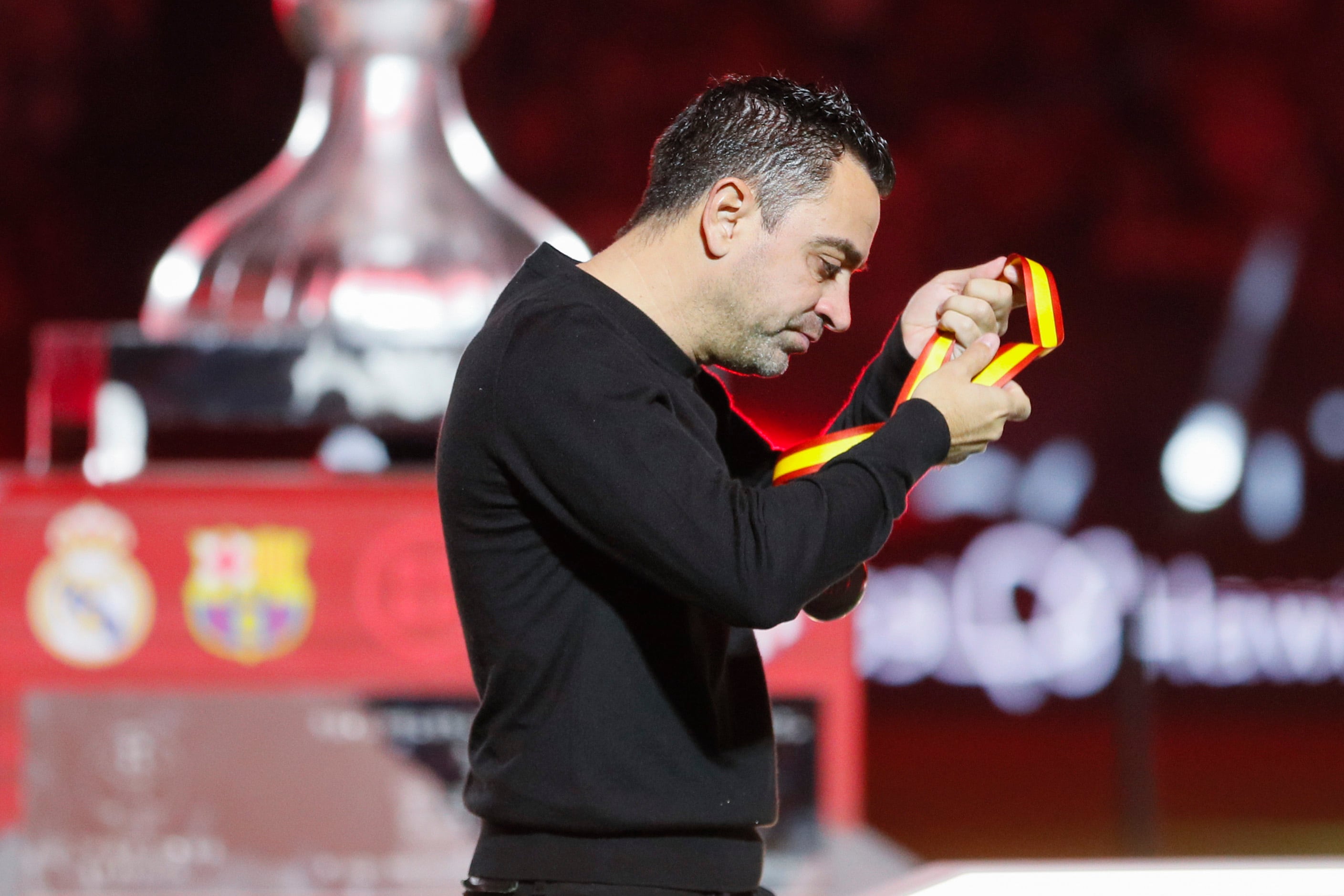 técnico del FC Barcelona Xavi Hernández se quita la medalla de segundo clasificado tras perder ante el Real Madrid en la final de la Supercopa de España.