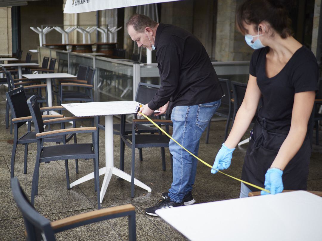 Camareros de una terraza de Navarra utilizan un metro para asegurarse de que las medidas de distanciamiento son las correctas entre los potenciales clientes de la terraza de un bar en el centro de Pamplona