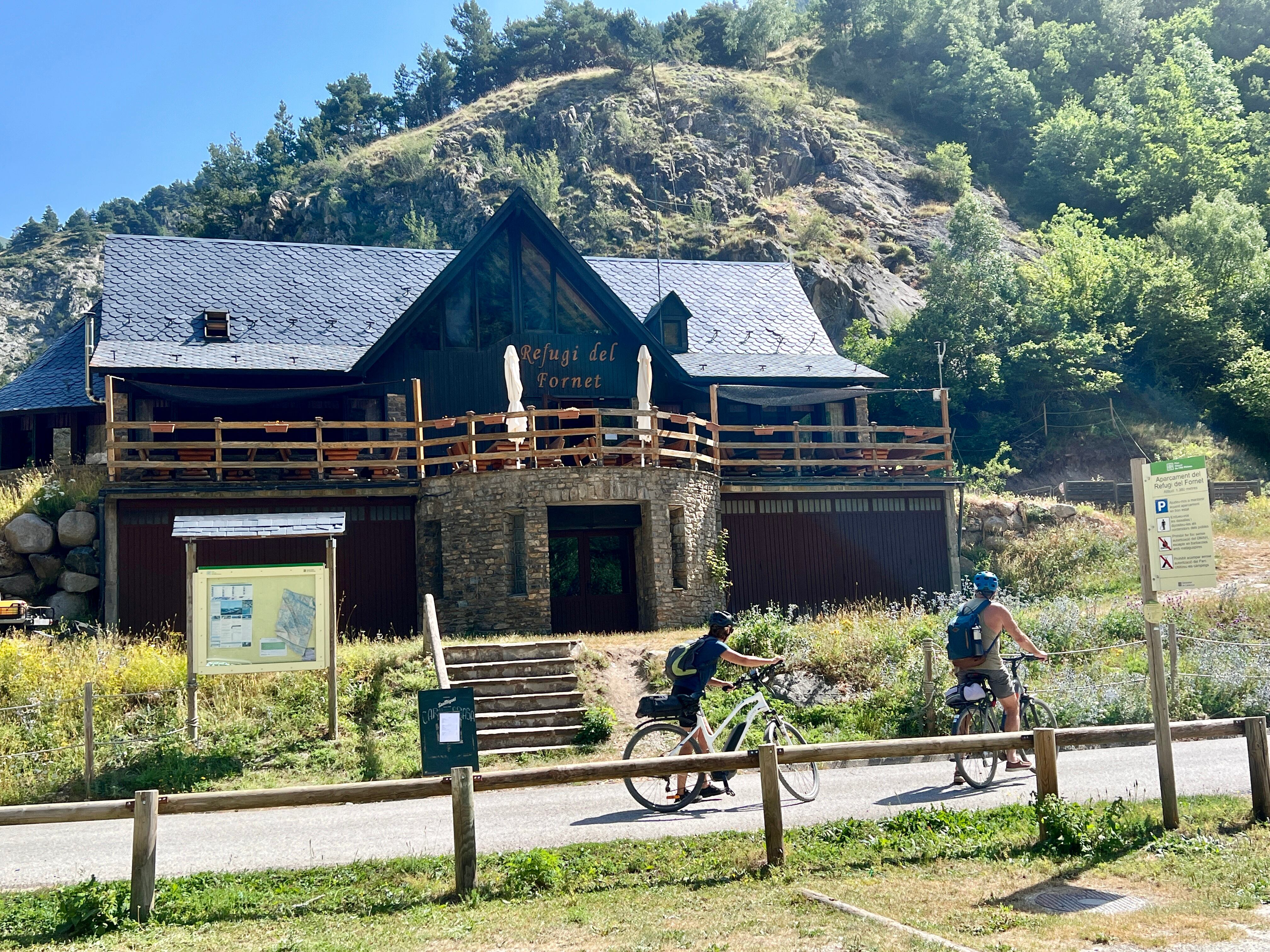 Dos ciclistes passant per davant del Refugi del Fornet, a Alt Àneu