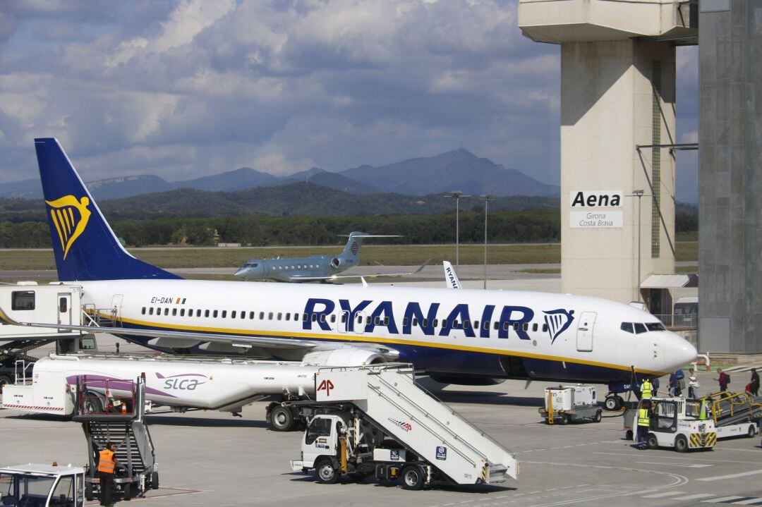 Un dels avions de Ryanair aterrats a l&#039;Aeroport Girona-Costa Brava amb la torre de control de fons