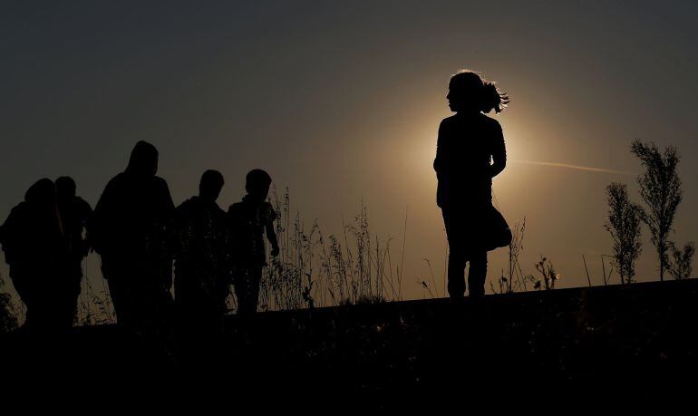  Inmigrantes caminando por las vias del tren en Roske , Hungria durante la puesta de sol del sábado.  REUTERS/Laszlo Balogh    