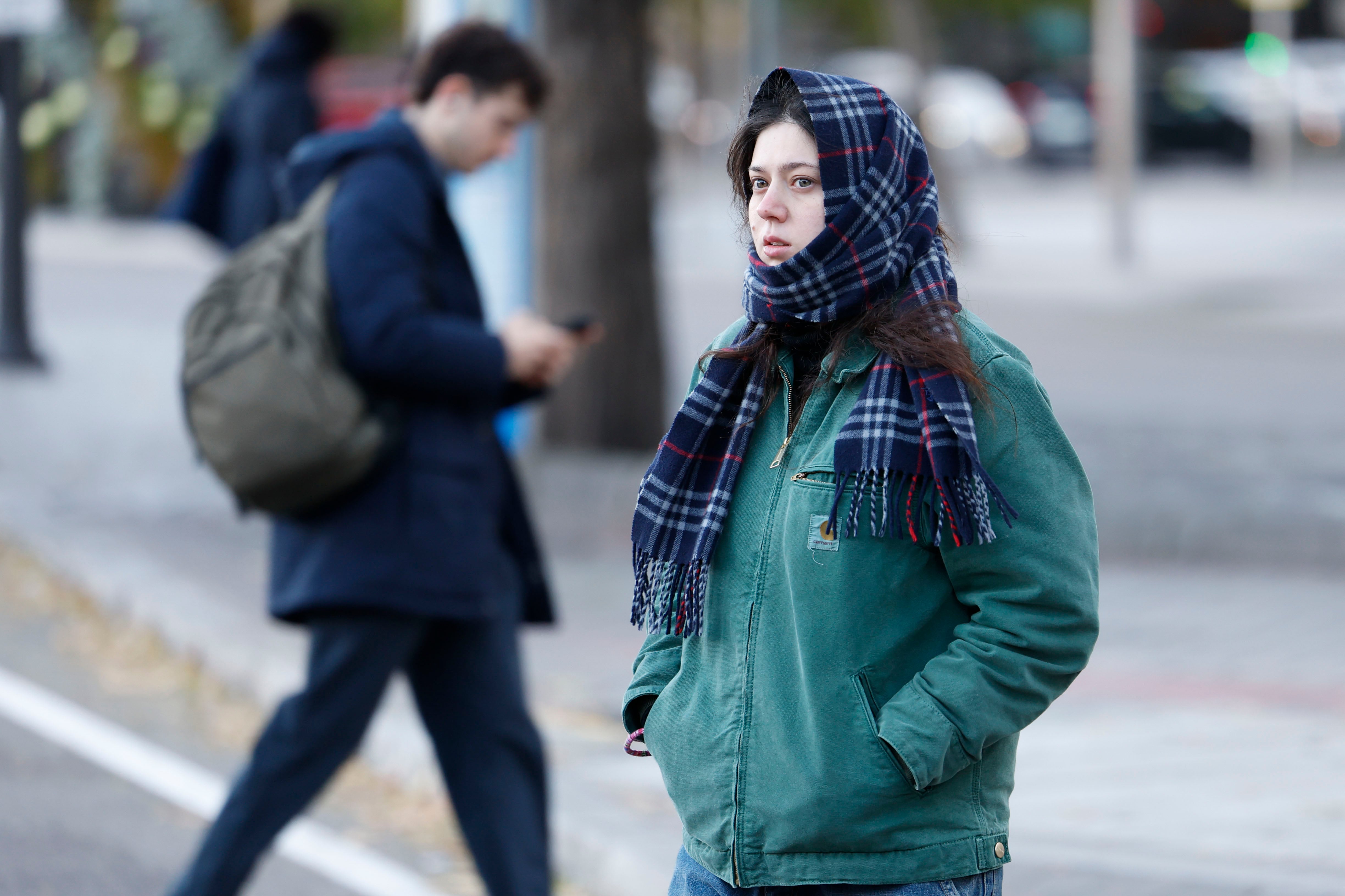 Una mujer se protege del frío mientras camina por Madrid.