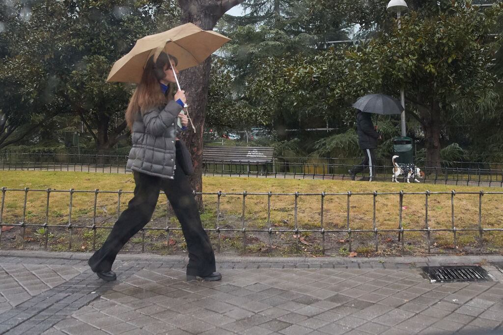 Una chica se protege de la lluvia con un paraguas.