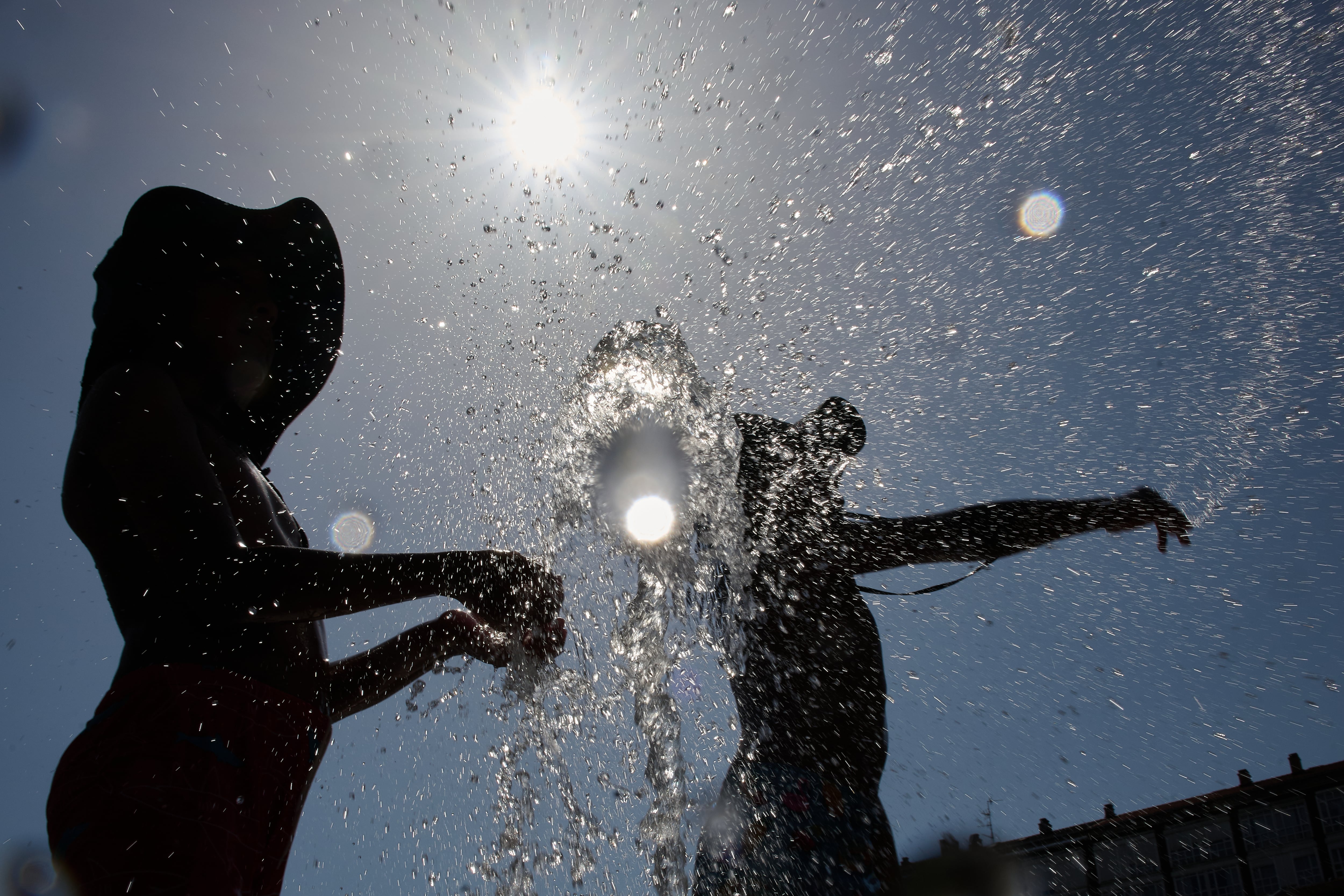 Varios jóvenes se refrescan en la fuente de la Plaza Yamaguchi de Pamplona. EFE/Iñaki Porto