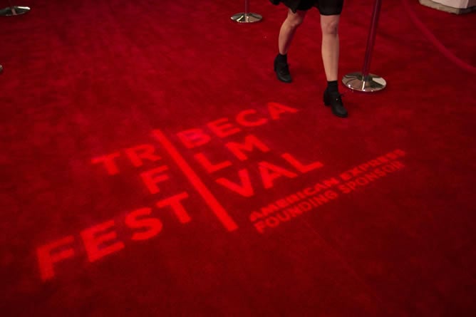 Una mujer camina sobre el logo del festival de Tribeca en la alfombra roja instalada para su inauguración