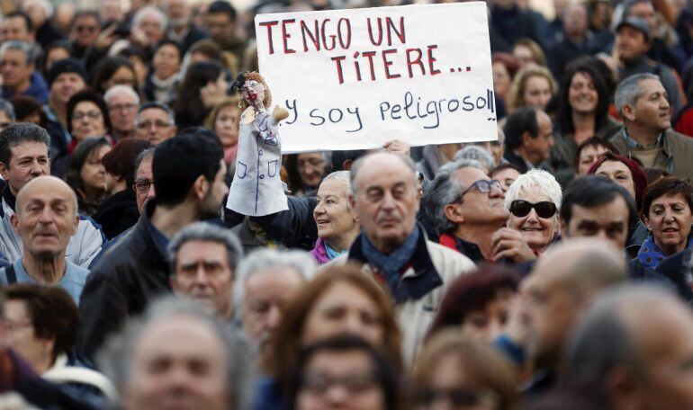 Una persona muestra un títere y un cartel alusivo durante la manifestación contra la corrupción en Valencia