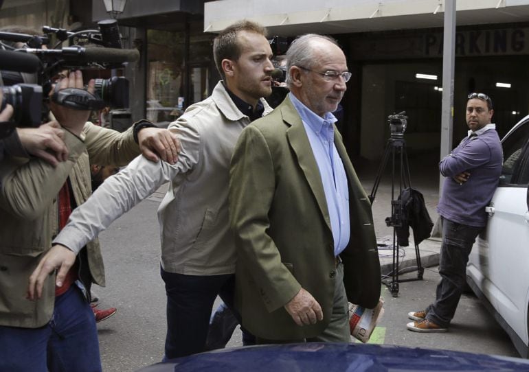 El exvicepresidente del Gobierno, Rodrigo Rato, acompañado de un guardaespaldas, sale de su domicilio donde numerosos medios de comunicación esperan noticias