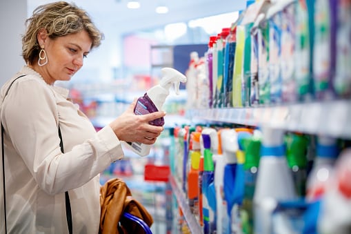 Una mujer observa la composición de un producto de limpieza