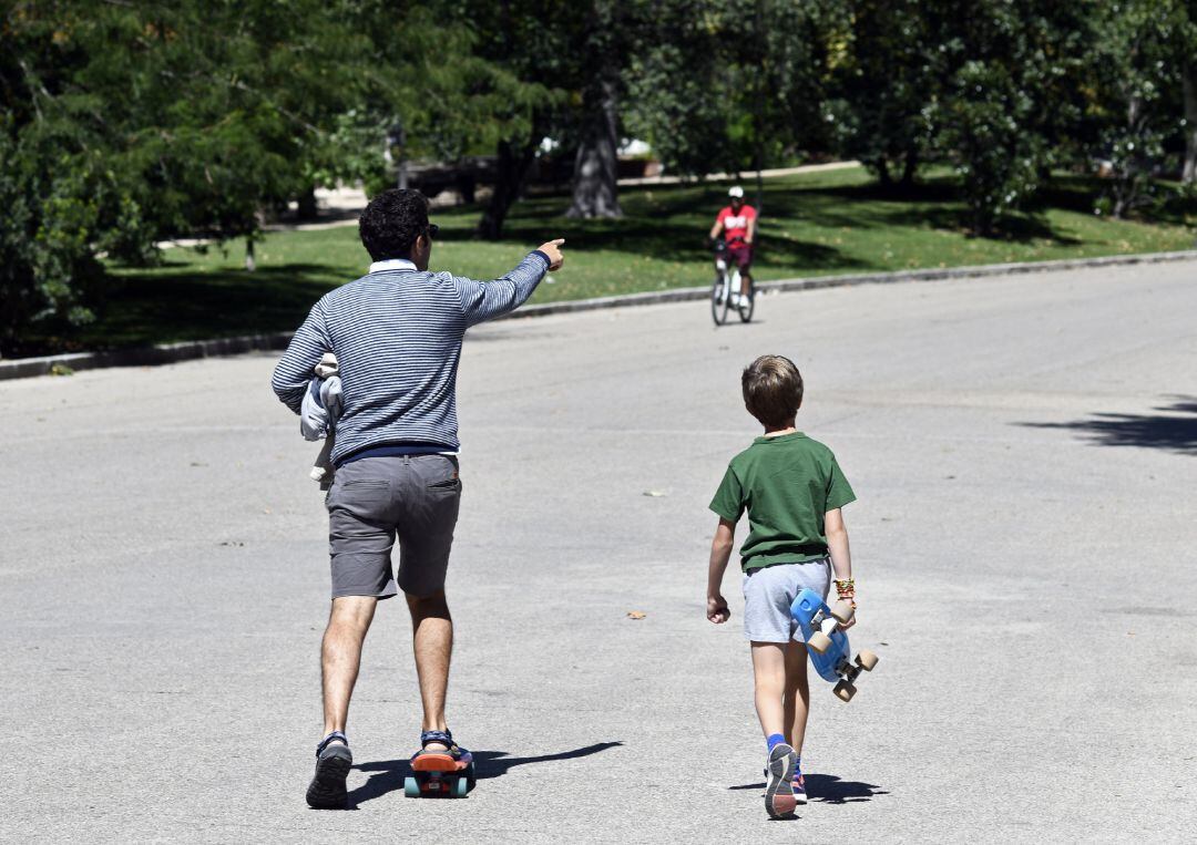 Un padre y un niño con, ambos con patinete, en un parque de Madrid.